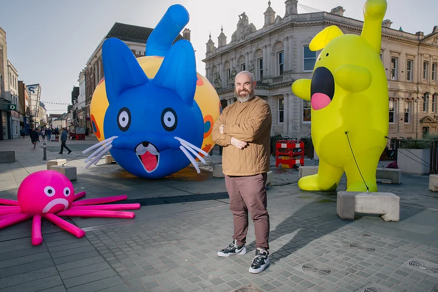A man standing in front of inflatable sculptures