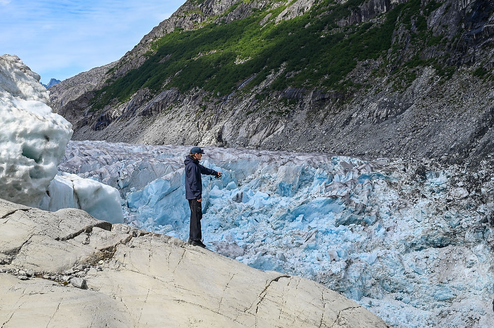 Sean Fagan, a University of Alaska Southeast climate researcher, points to where the Mendenhall Glacier is retreating into Suicide Basin on Aug. 13, 2025. The glacier functions as a natural dam. (Jasz Garrett / Juneau Independent)
