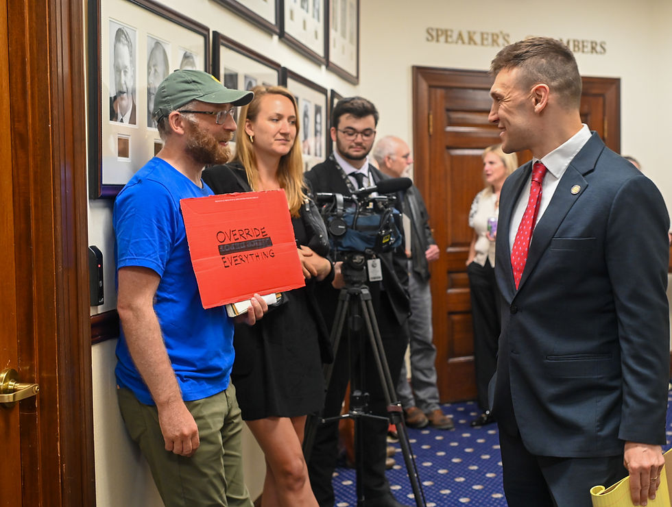 Sen. Forrest Dunbar, D-Anchorage, talks to demonstrators and reporters in a hallway of the Alaska State Capitol on Saturday, Aug. 2, 2025. Dunbar returned from military deployment service overseas to attend the session for a single day to cast votes on two veto overrides, including one involving education funding that got the minimum votes needed. (Jasz Garrett / Juneau Independent)