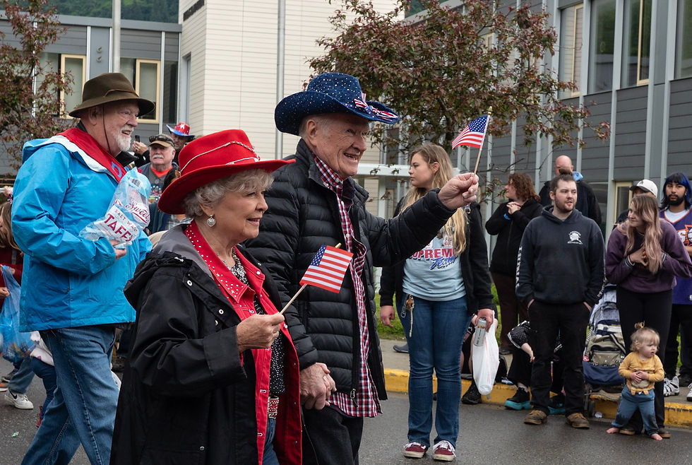 Judy and Jerry Tufto walk in the Douglas parade on Saturday, July 4, 2026. Bruce Botehlo tosses taffy behind them. (Jasz Garrett / Juneau Independent)
