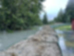 The Mendenhall River floodwater (left) is seen a foot below a single level of the HESCO barriers on Riverside Drive near Melvin Park on Wednesday, Aug. 13, 2025. (Laurie Craig / Juneau Independent)