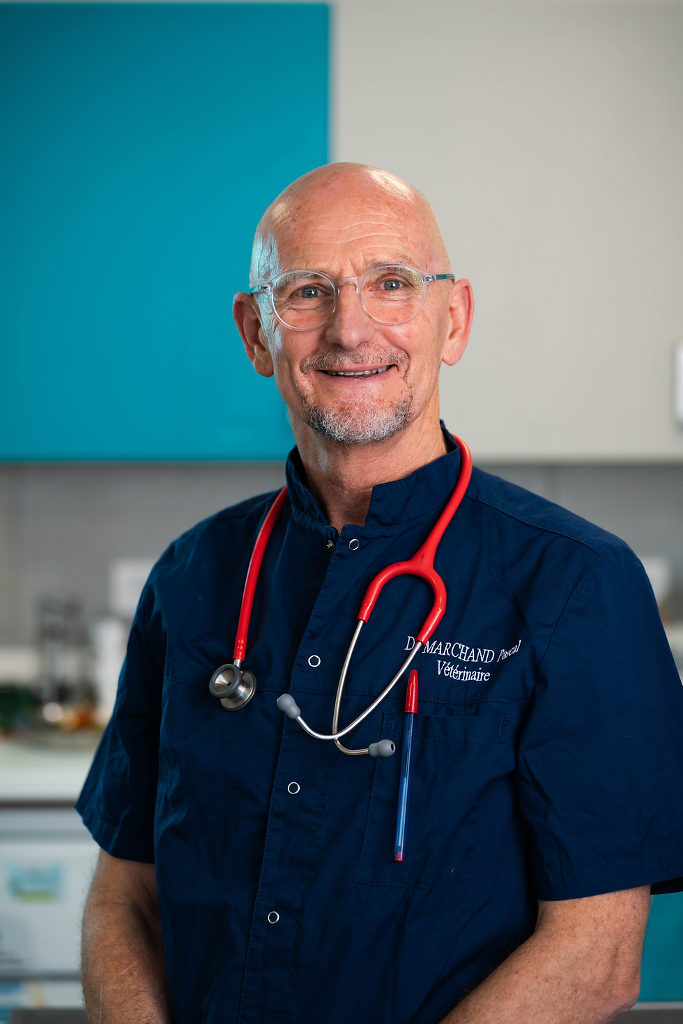 Médecin souriant en uniforme bleu avec stéthoscope rouge.