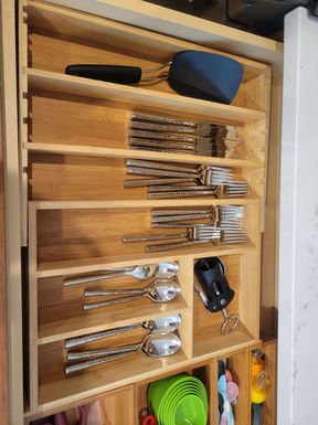 Organized silverware drawer with neatly sorted forks, knives, spoons, and kitchen utensils.