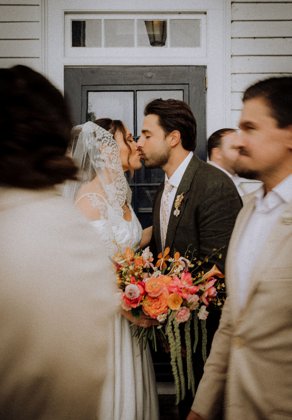 Bride and groom kissing with vibrant wedding bouquet
