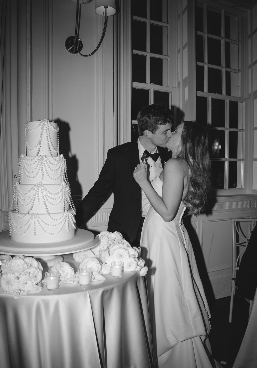Black and white wedding couple kissing near cake.