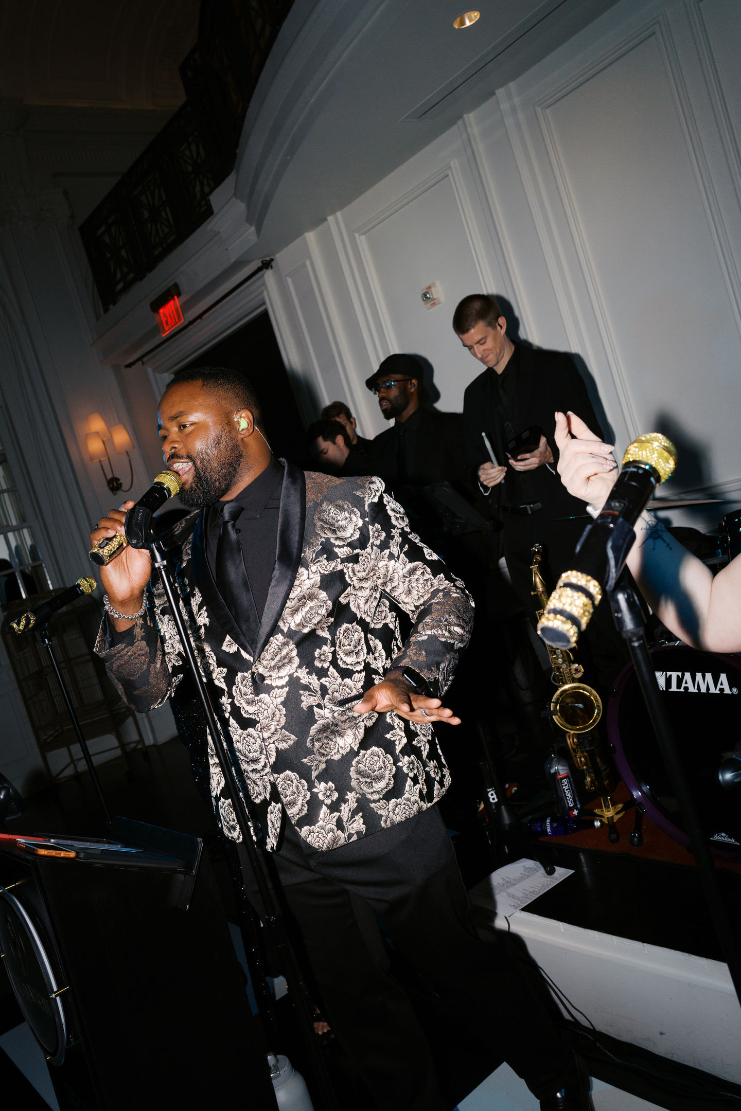 Man singing with a band in a dimly lit venue.