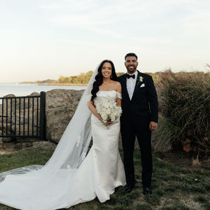 Bride and groom standing outdoors, smiling together.