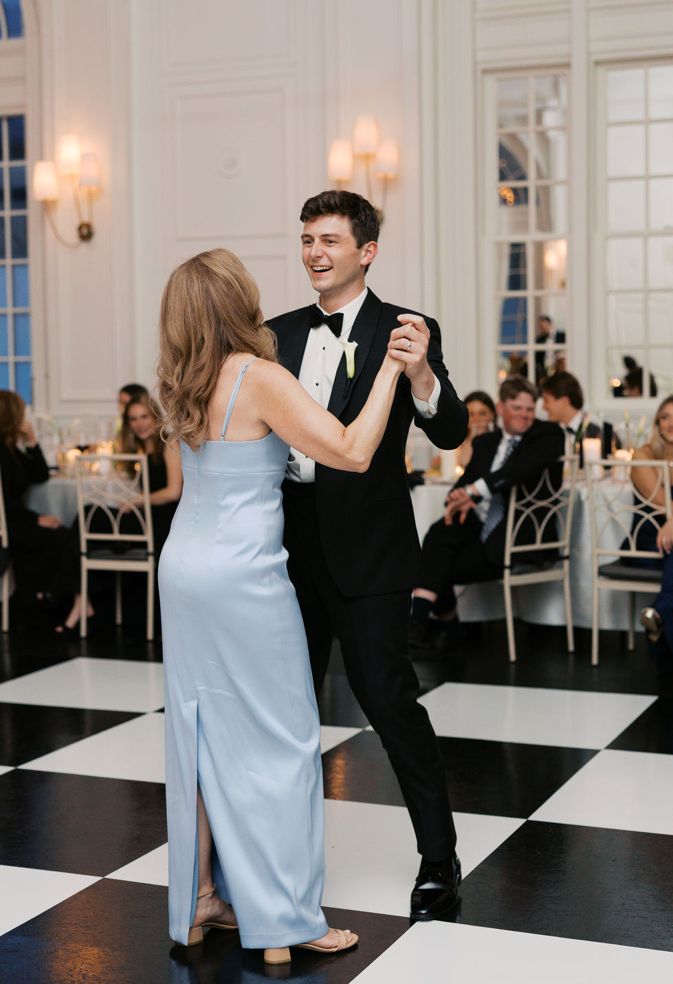 Groom and mother dancing at an elegant event.