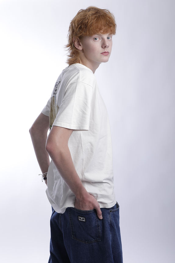 Ginger man with body facing away from camera and head turned back over the shoulder facing the camera