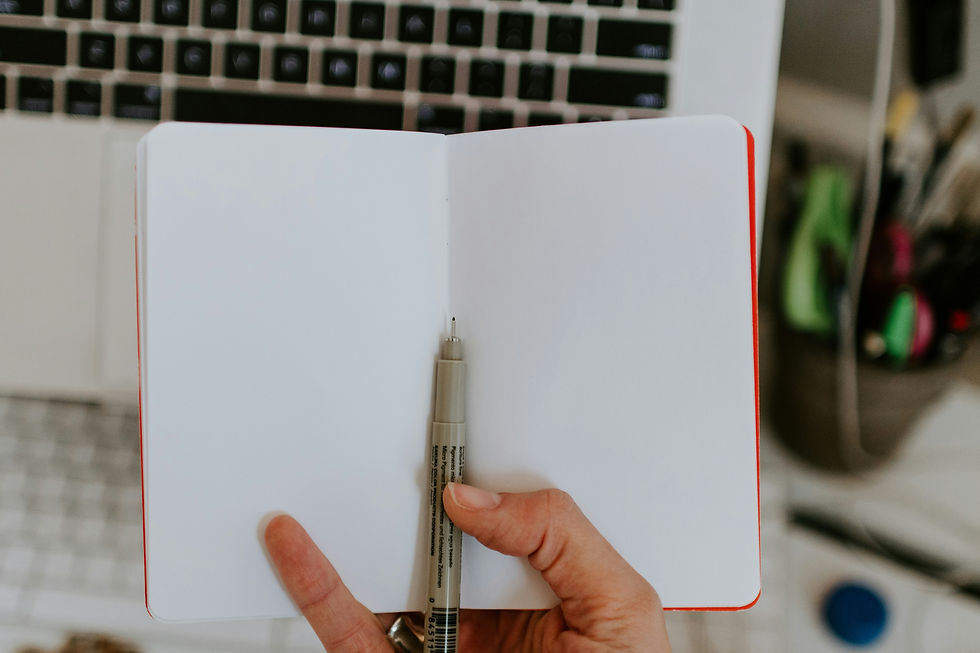 A hand holds a blank journal with a pen resting inside.