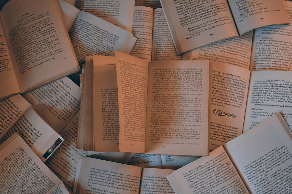 A collection of open books lay on a surface on top of each other.