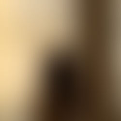 A woman standing quietly by a window with soft morning light streaming in.