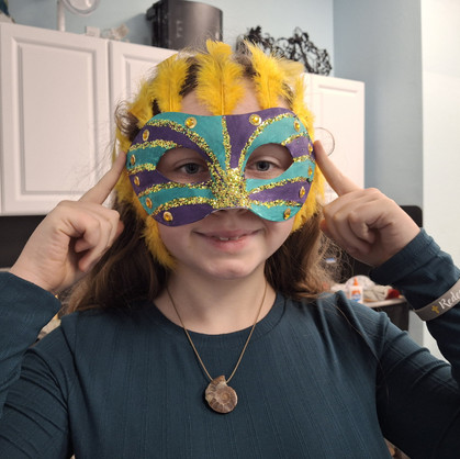 Eighth grade student Roselynn Breunig models her completed Mardi Gras mask during the Mardi Gras Maskerade student exhibit at Evoke Studio & Gifts by Melissa Mitchell.