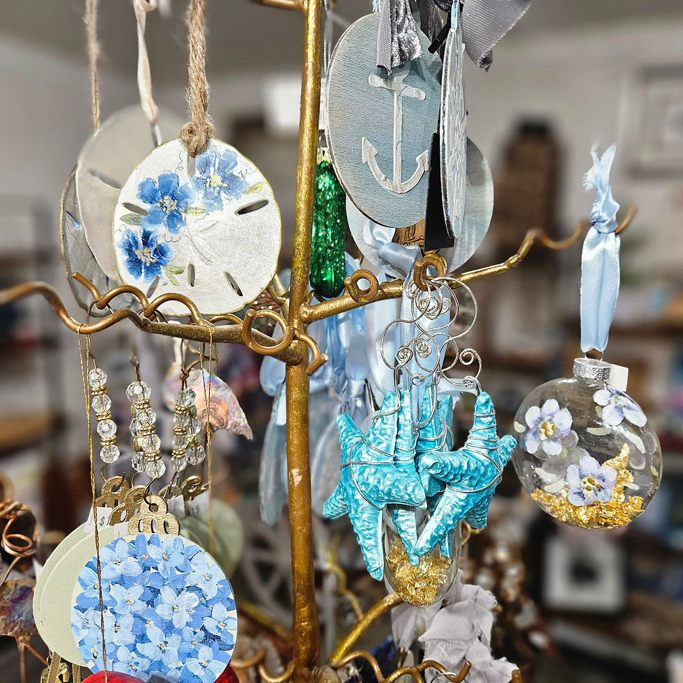 Handmade coastal-themed ornaments—including sand dollars, anchors, blue florals, and starfish—displayed on a gold tree inside Evoke Studio & Gifts, photographed by Melissa Mitchell.
