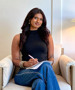 Sarayu Srinivasan seated in an armchair, writing in a notebook