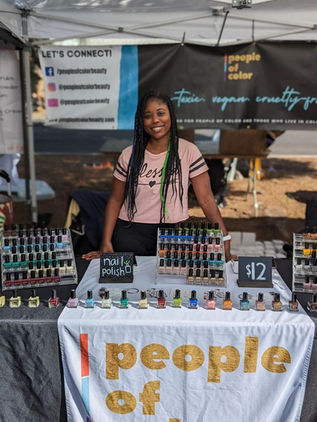 Image of founder Jacque Carrington at a table stand featuring an assortment of her nail polishes.