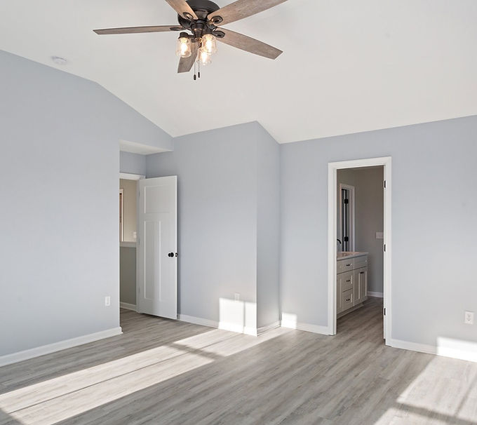 Spacious bedroom with vaulted ceiling, ceiling fan, and gray walls
