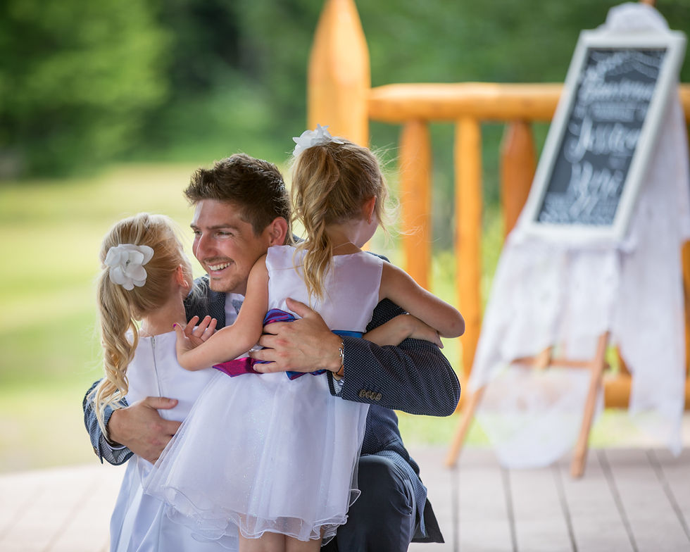 A groom hugs his two daughters at his wedding
