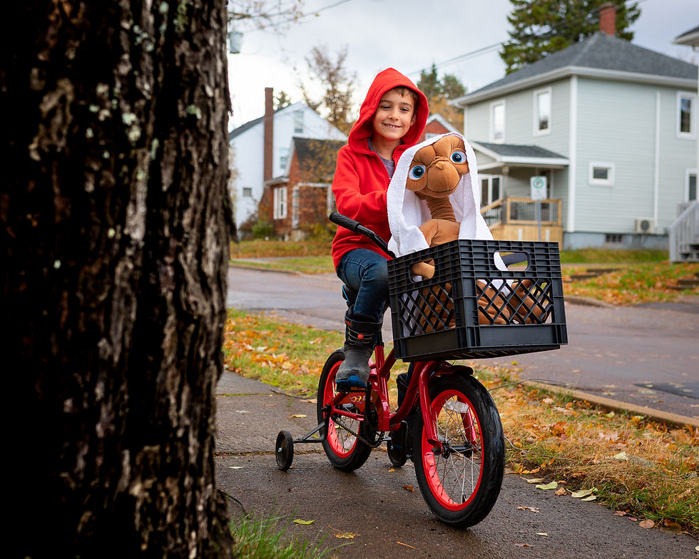 A kid on a bicycle with the E.T. character in front of it.