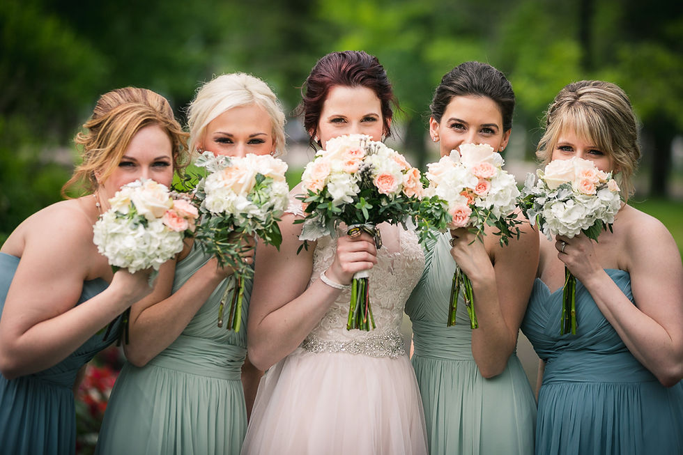 Bride and bridesmaids covering their faces with their bouquets