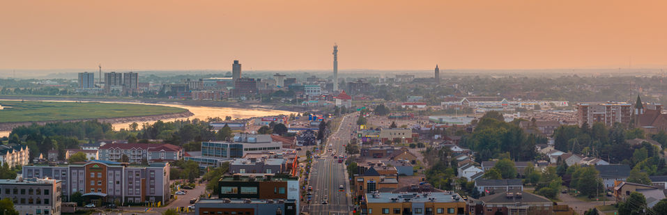 Panoramic aerial photo of urban development in Moncton and Dieppe, New Brunswick, with a warm, golden light at sunset.
