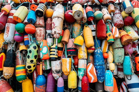 Colourful fishing buoys hung on a wall.