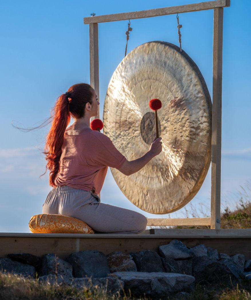 a woman plays a gong
