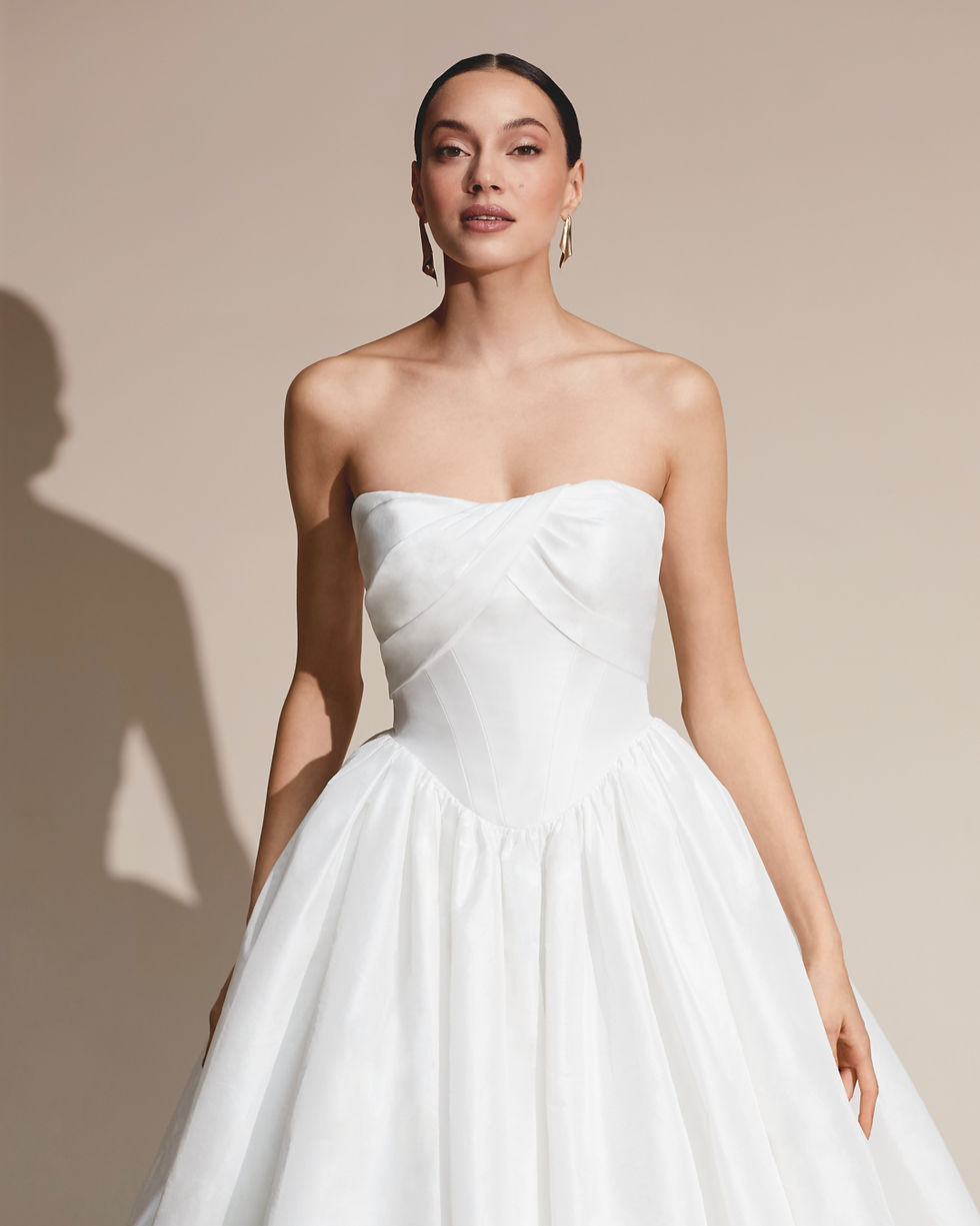 Close-up view of a draped corset bodice with a Basque waist on an ivory wedding dress.