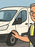 A man in a hiviz vest inspecting a white van