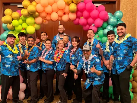 Masterpiece Cuisine catering team smiling together in matching blue shirts for a party.