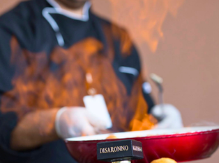 Masterpiece Cuisine’s chef flambeing a donut, at an event.