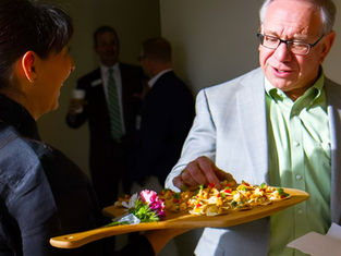 Man sampling the appetizers at an office party, catered by Masterpiece Cuisine. The right holiday party catering turns a calendar obligation into something people happily attend.