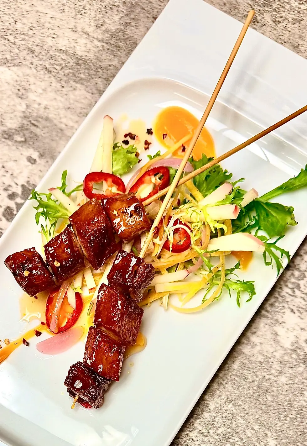 Plated skewers, garnished with vegetables and sauce, catered by Masterpiece Cuisine.