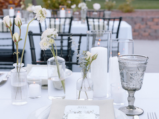 Elegant outdoor event table setup with candles, floral centerpieces, and menu card styled by Masterpiece Cuisine.