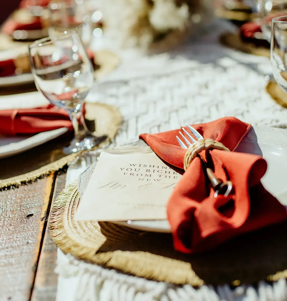 Masterpiece Cuisine wedding catering place setting with an orange napkin and custom card on a wooden table.