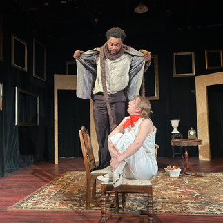 Man dressed as dog stands over woman dressed as moor-hen and holds his jacket open over her