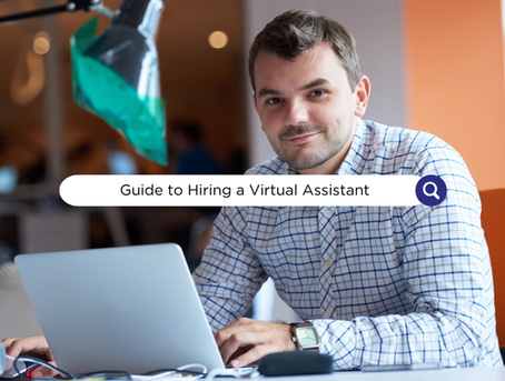 Man in checked shirt working on laptop in modern office, smiling. Text overlay reads: Guide to Hiring a Virtual Assistant.