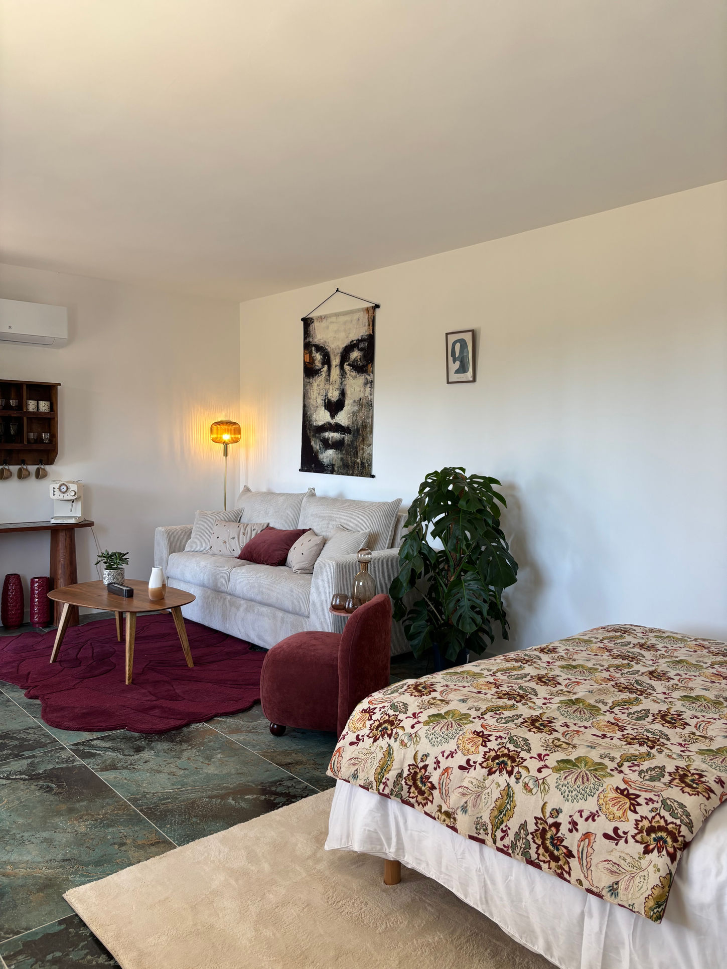 Suite avec un grand lit et un grand canapé convertible confortable et moelleux, l'espace a une décoration bois et carrelage bleu vert marbré, matériaux naturelles et couleurs de la décoration beige et lis de vin. Suite appartenant au boutique Horizon à Carcassonne