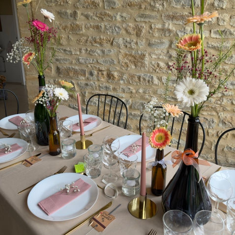 Table de réception de mariage décorée de petits vases et de bouteilles fleuris