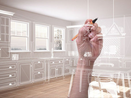A hand with a pen sketches a kitchen design overlay in a modern room. Light tones, windows in background. Creative and focused mood.