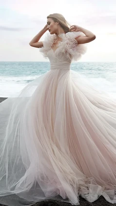 Pink a-line wedding dress crafted wholly of antique rose tulle with sweetheart neckline and tulle draping. The short sleeves are sculptural yet light thanks to the tulle ruffles.