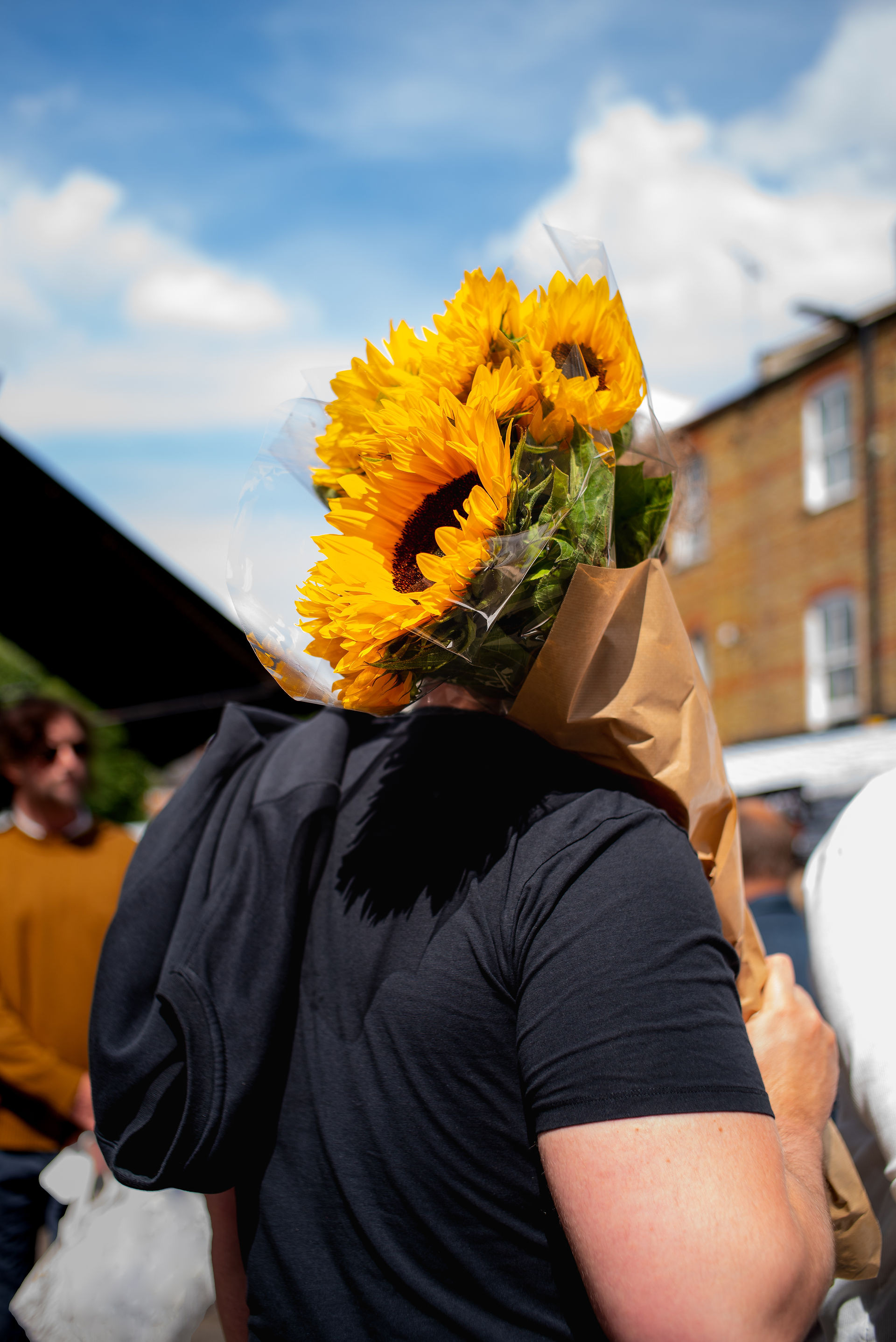 London flower market man standing holding a fresh bunch of sunflowers in the summer heat