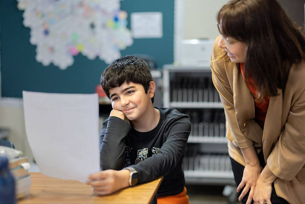 A Bullis Charter School student looks at a paper as a teacher looks on.