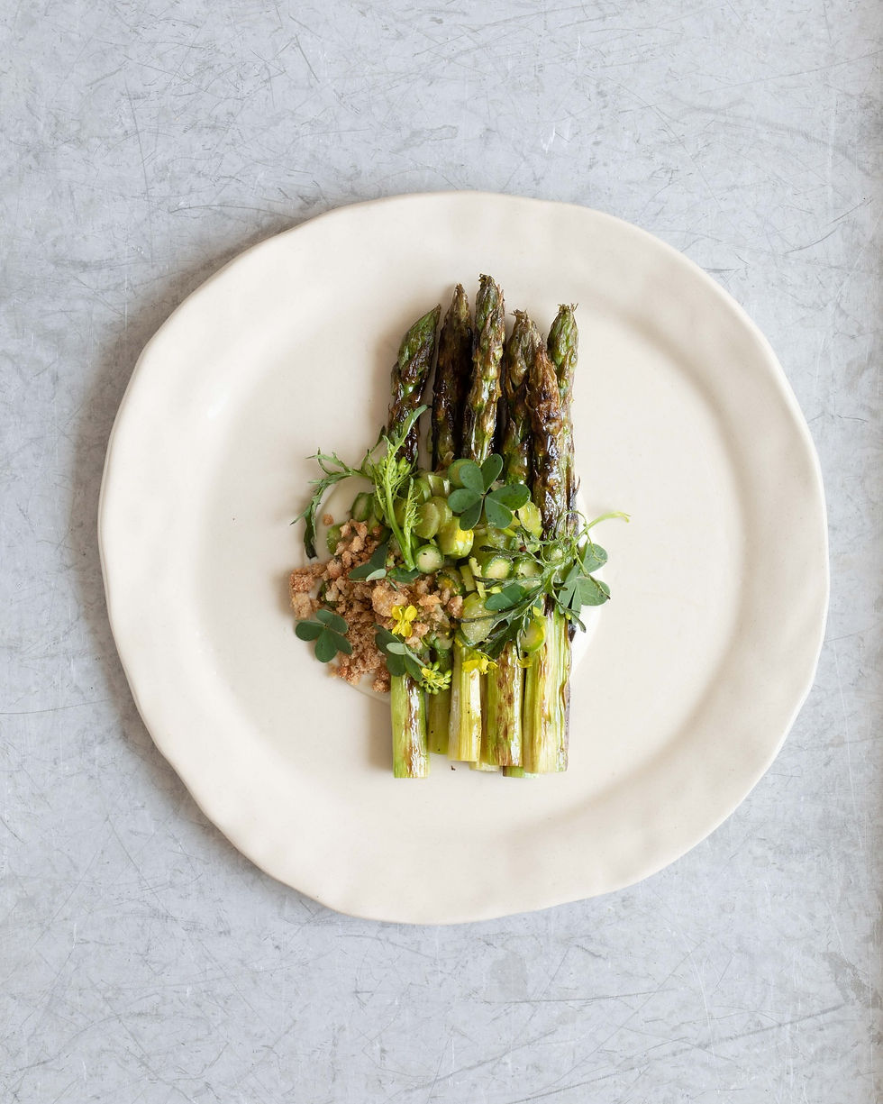 Plate of fresh asparagus, field herbs and garden vegetables harvested from the garden and served at the table