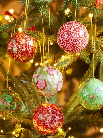 Large hand painted Christmas bauble on a pine tree