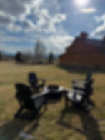 Western Colorado Barn Wedding Venue that offers a guest experience by having a fire pit.  Firepit in front of rustic, modern barn with 4 black lounge chairs