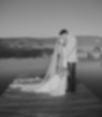 Bride and Groom standing on dock of a peaceful pond kissing at Colorados barn Wedding Venue near Grand Junction, co on the Western Slope