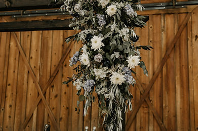 Wooden Arch adorned with spring florals of white and green greenery.