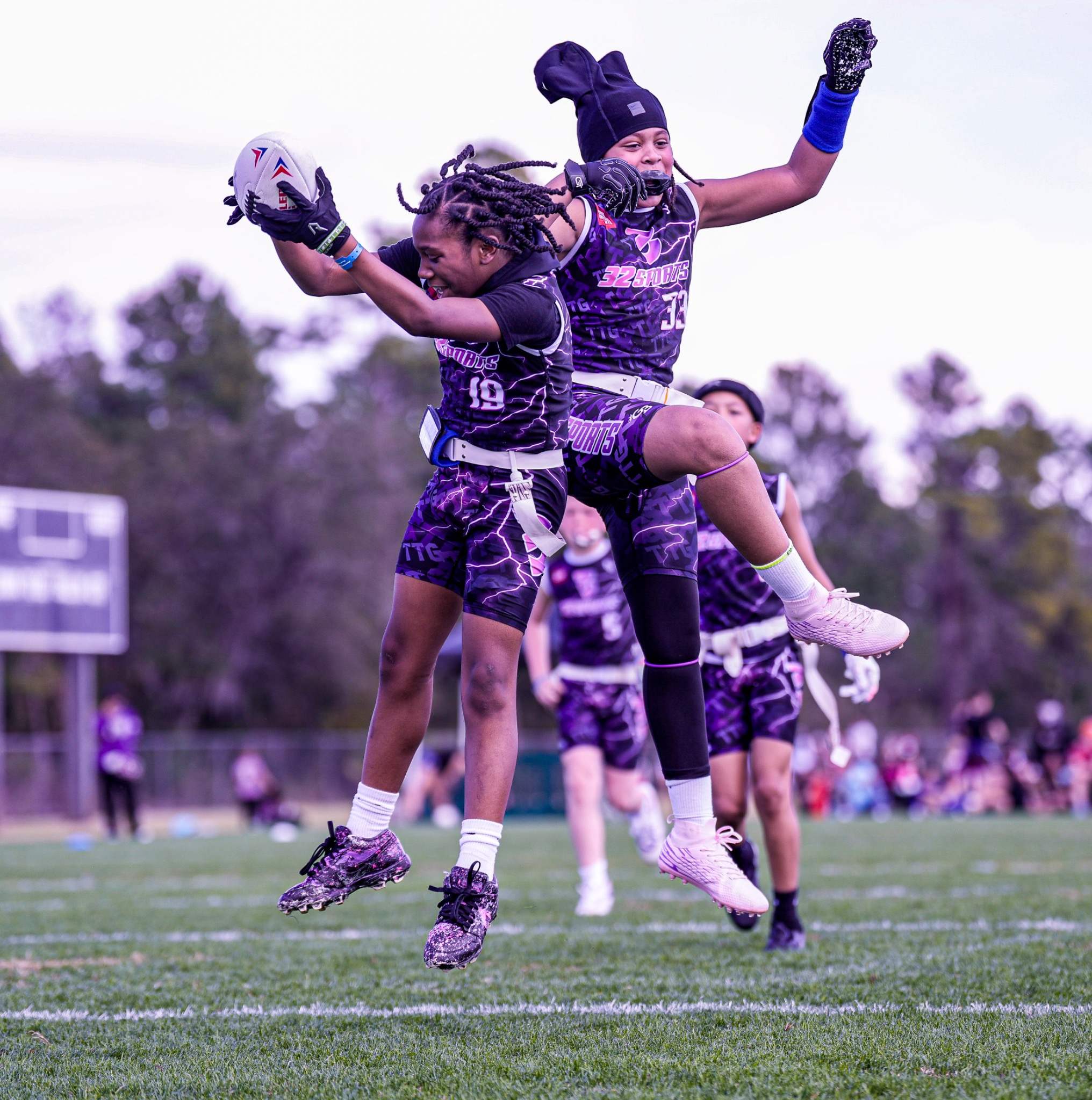 Two 32 Sports flag football teammates celebrating together on the field