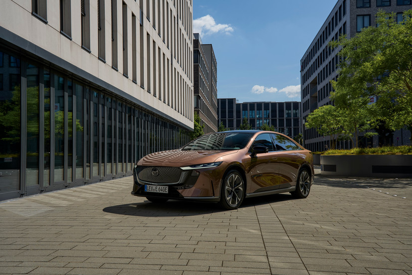 Neuer Mazda 6e Elektro Limousine 2026 in der Ausstattung Takumi vor einem Gebäude - Frontansicht